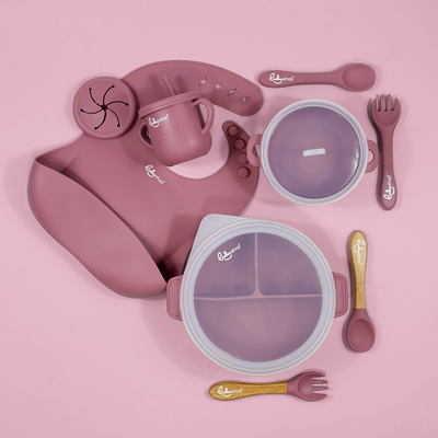 Lulushop 9-piece baby feeding set in Pink Daisy, featuring silicone suction plate, bowl, bib, cup, and utensils.