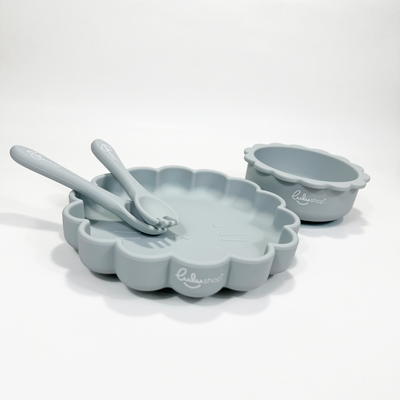 Sky blue sunshine-shaped silicone baby feeding set viewed from an angled front-top perspective, showing plate, bowl, fork and spoon